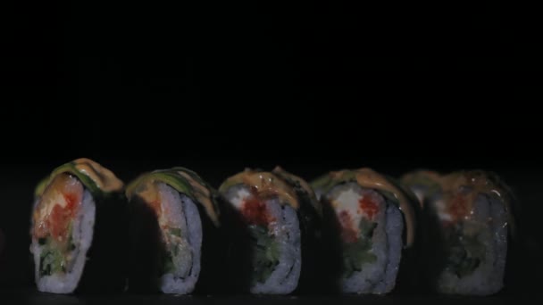 Sushi com fatias de salmão e pepinos frescos. Sushi apetitoso numa tábua de pedra preta. Close-up — Vídeo de Stock