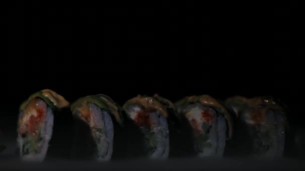 Sushi with slices of salmon and fresh cucumbers. Appetizing sushi on a black stone board. Close-up — Stock Video