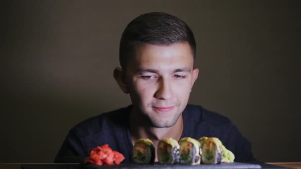 Голодный человек смотрит на суши, не ест, ждет — стоковое видео