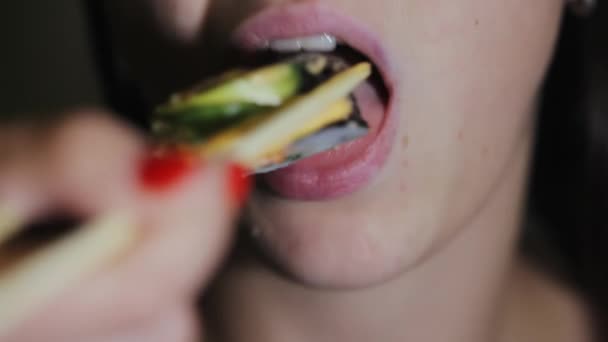 Красивая молодая женщина ест палочки для суши. Женский рот ест суши — стоковое видео