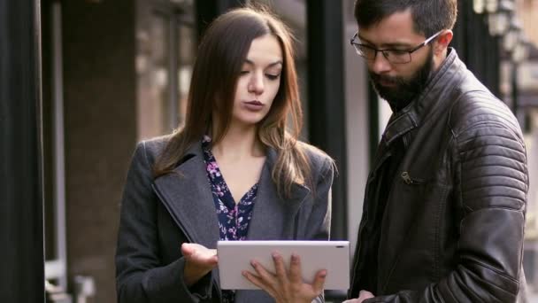 Działalności człowieka i kobieta mówi stojący i wykorzystania komputera tablet na zewnątrz — Wideo stockowe