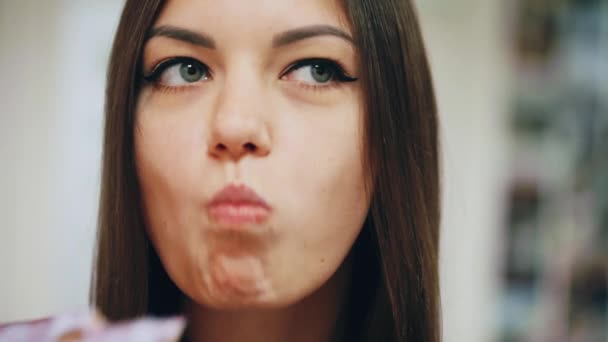 Close-up portret van mooi blij meisje eten van een donut, genieten van een snack op het werk — Stockvideo