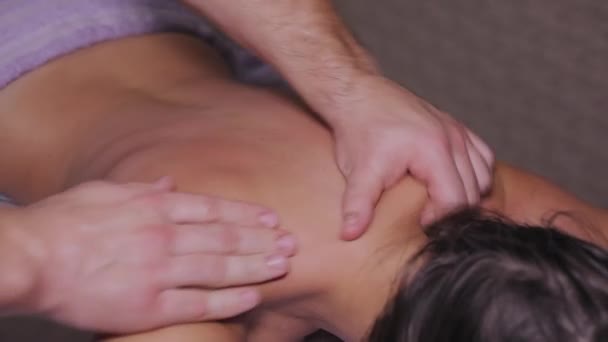 Hombre terapeuta haciendo masajes para mujer. Joven atractiva mujer se encuentra en el sofá y disfrutar de masaje en el cuello, primer plano — Vídeo de stock