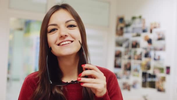 Portret van de mooie vrouw glimlach voor de camera, zet op bril en geeft duimen op — Stockvideo