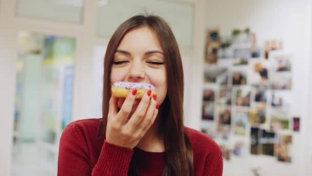 Glad tjej äta en munk, njuta av ett mellanmål på jobbet — Stockvideo