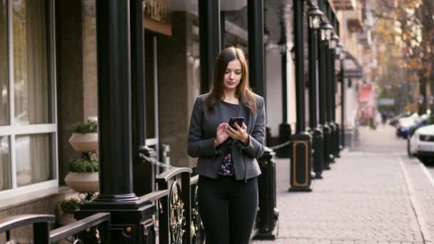 Mooie zakenvrouw op straat met behulp van de smartphone app, surfen op internet, slow-motion — Stockvideo