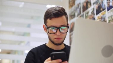 Genç erkek programcı, bir dizüstü bilgisayar ve telefon üzerinde çalışan geliştirici. Bir mobil uygulama geliştirir