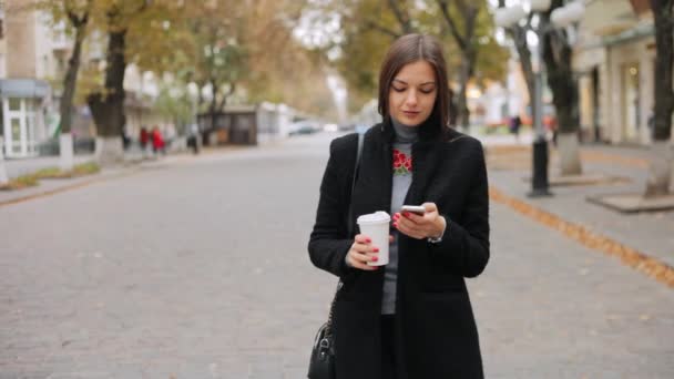 Mulher verifica e-mail, olha para notícias, bate-papos no telefone e bebe café na rua — Vídeo de Stock