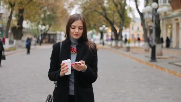 Frau geht auf die Straße, checkt Post, schaut sich Nachrichten am Telefon an und trinkt Kaffee — Stockvideo
