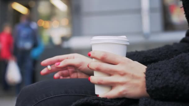 Close-up de uma menina bebendo café de um copo de papel, fumando um cigarro — Vídeo de Stock