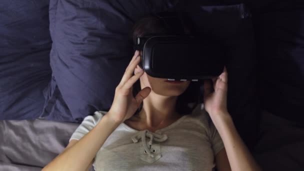 Vista superior de la mujer joven acostada sobre almohadas en la cama uso de la realidad virtual — Vídeos de Stock