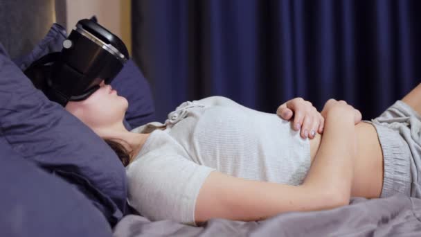 Jonge vrouw liggend op kussens op de bed gebruik virtual reality, Vr video bekijken — Stockvideo