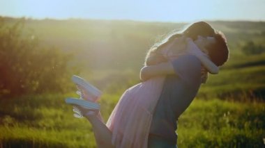 Genç güzel çift kucak ve öpücük, Doğa, alan bir günbatımı.