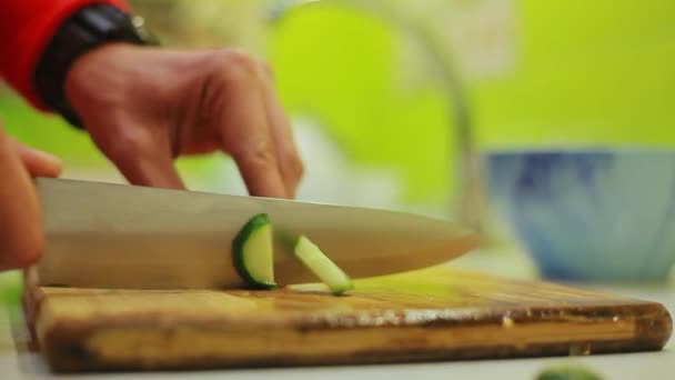 Manos de hombre corta pepino con cuchillo en tablero de madera para ensalada de verduras — Vídeo de stock