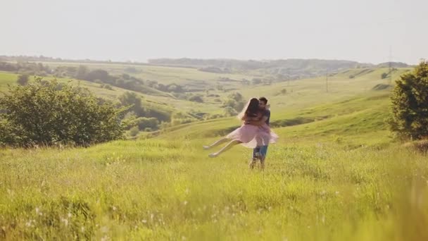 Молодая привлекательная пара танцует и обнимается на широком открытом желтом поле в солнечный день крупным планом — стоковое видео