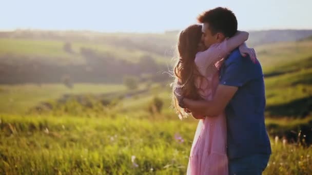 Um jovem lindo casal abraço e beijo, natureza, campo ao pôr do sol . — Vídeo de Stock