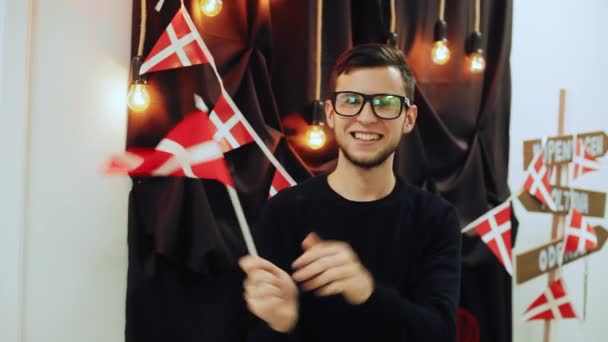 Bonito homem segurando bandeira dinamarquesa, acenando e sorrindo olhando para a câmera. Retrato de feliz viajante . — Vídeo de Stock