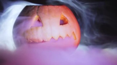 Bir arka plan siyah yakın çekim duman etrafında oyulmuş Cadılar Bayramı Balkabağı.