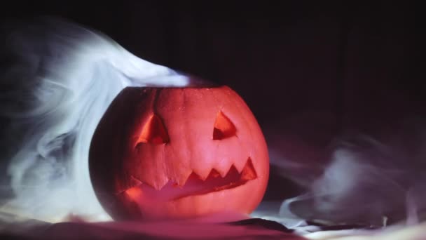 Abóbora de Halloween esculpida, em torno da fumaça em um fundo preto close-up . — Vídeo de Stock