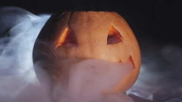 Abóbora de Halloween esculpida, em torno da fumaça em um fundo preto close-up . — Vídeo de Stock