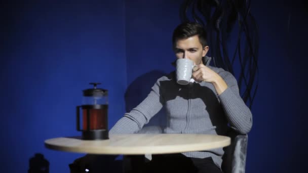 Jeune homme assis dans un café sombre et fumant e-cigarette vape et boire du café chaud . — Video