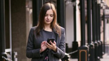 Akıllı telefon app kullanarak, internet ve gülümseme yavaş hareket sörf Caddesi üzerinde güzel işkadını portresi.