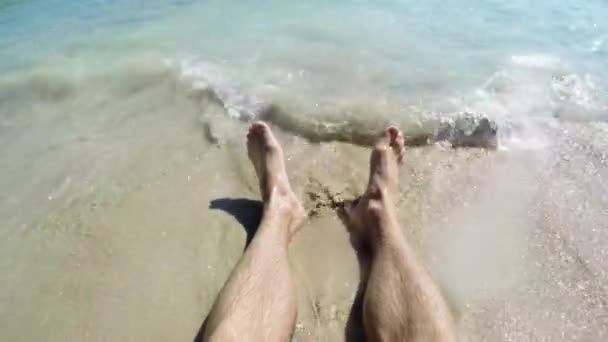 Mans pés lavados por ondas do oceano e enterra-los na areia. Close-up de um pé de homem deitado na praia — Vídeo de Stock