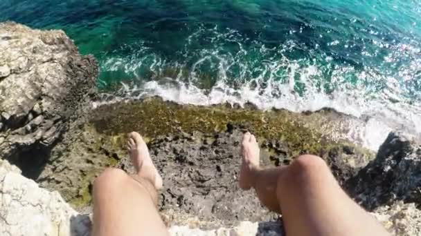 Första person perspektiv unga manliga upptäcktsresande sitter på klippkanten ovanför havet — Stockvideo