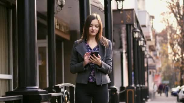 Όμορφη επιχειρηματίας στο δρόμο χρησιμοποιώντας το smartphone app, σερφάρισμα στο διαδίκτυο και χαμόγελο αργή κίνηση. — Αρχείο Βίντεο