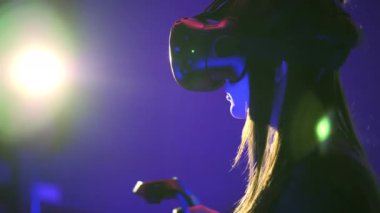 Duygusal kadın oyun 3d sanal gerçeklik oyunu. Sürgünler etrafa denetleyicileriyle. VR kulaklık, artalanları ışık flare giyen kız