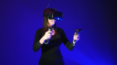 Vr kulaklık gamepad, uzaktan kumanda kullanarak genç kadın eğlenmek ve etkileşimli video oyunu oynayabilirler. Sanal gerçeklik kask mavi zemin üzerine
