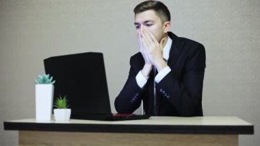 Dizüstü bilgisayar, ofis masa başına oturmuş yorgun ile genç işadamı