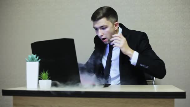 Zakenman is geschokt door laptop verdeling, rook die afkomstig is van computer — Stockvideo
