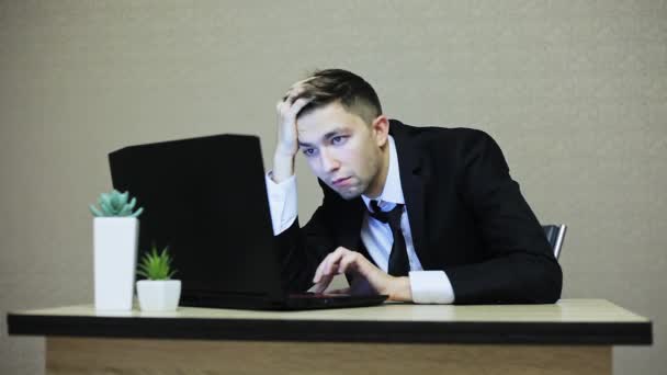 Втомився і нудний бізнесмен у костюмі, що працює на ноутбуці — стокове відео