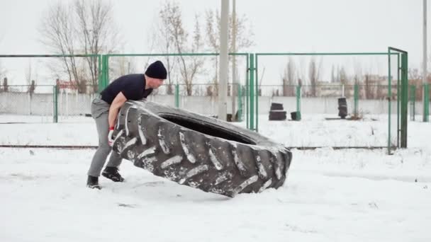 Muskularny mężczyzna ćwiczeń crossfit - podnoszenia duże gumowe opony w boisko sportowe — Wideo stockowe