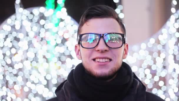 Elegáns fiatalember látszó-on város fő Christmas tree fények tükröződik a szemüveg — Stock videók