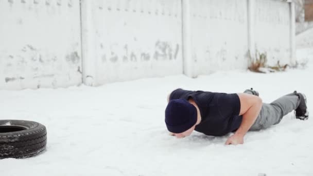 Мужчина занимается спортом в снежную зиму, отжимается — стоковое видео