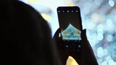 Kadın telefonu şehrin ana Noel ağacına yeni yıl kutlamaları fotoğraf alır