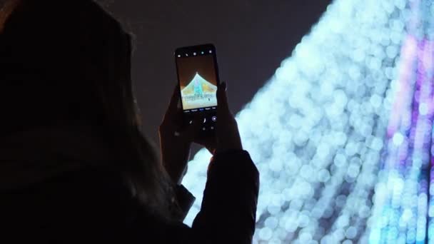 Женские фотографии на телефоне главный город Рождественская елка на новогодние праздники — стоковое видео