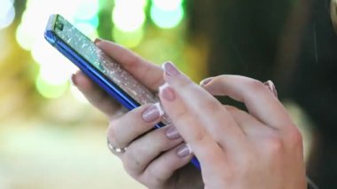 Bir kadının el closeup cep telefonu app karlı akşam, Noel ve yeni yıl kullanır.