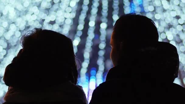 一对夫妇近距离地看着城市的欧洲新年树, 花环上的灯光模糊了 — 图库视频影像