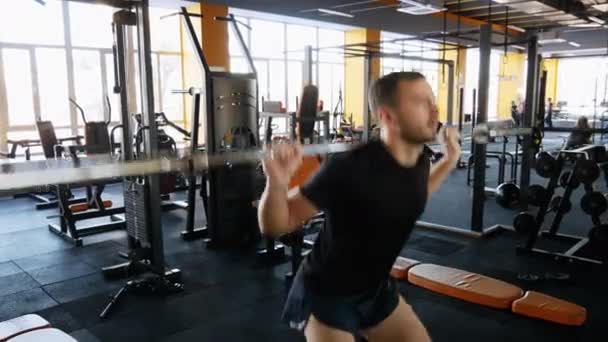 El deportista se calienta antes del entrenamiento. Hombre sentadilla con barra en el gimnasio — Vídeos de Stock