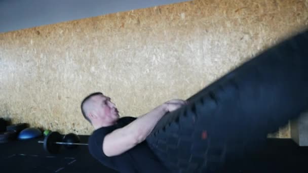 Человек поднимает большую шину во время разработки кроссфит упражнения - фитнес-тренировки концепции — стоковое видео