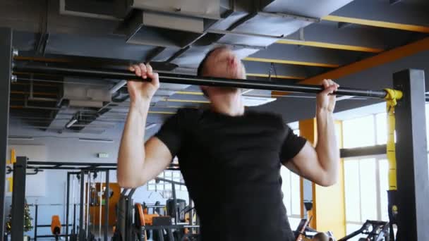 Primer plano Atleta hombre musculoso tirando hacia arriba en la barra horizontal. Fitness masculino en un gimnasio . — Vídeos de Stock