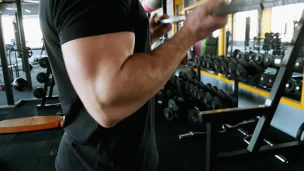 Muskulös man med stora biceps lyfta vikter i ett gym. Lyfta skivstång i närbild — Stockvideo