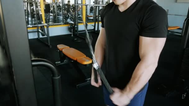 Primer plano del atleta fuerte bombea los músculos en el simulador. Hombre tríceps de entrenamiento en el gimnasio — Vídeo de stock