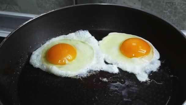 Женщина посыпает специи на яйца, которые жарятся в сковороде — стоковое видео