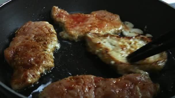 Σεφ αναστρέφει χοιρινή μπριζόλα σε ένα τηγάνι. Γκρο πλαν από μπριζόλες τηγανίζονται σε τηγάνι — Αρχείο Βίντεο
