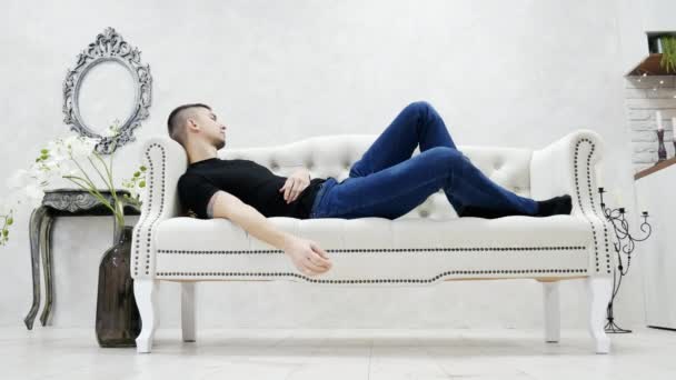 Молодой уставший мужчина спит на диване в роскошной гостиной, спит во время перерыва . — стоковое видео