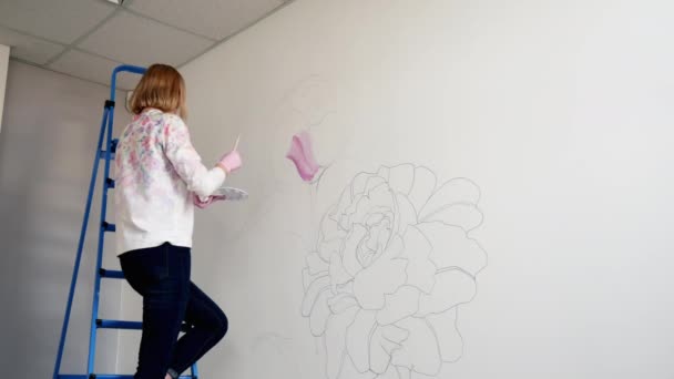 Graffiti žena umělec maluje pivoňky na bílé zdi se štětcem — Stock video